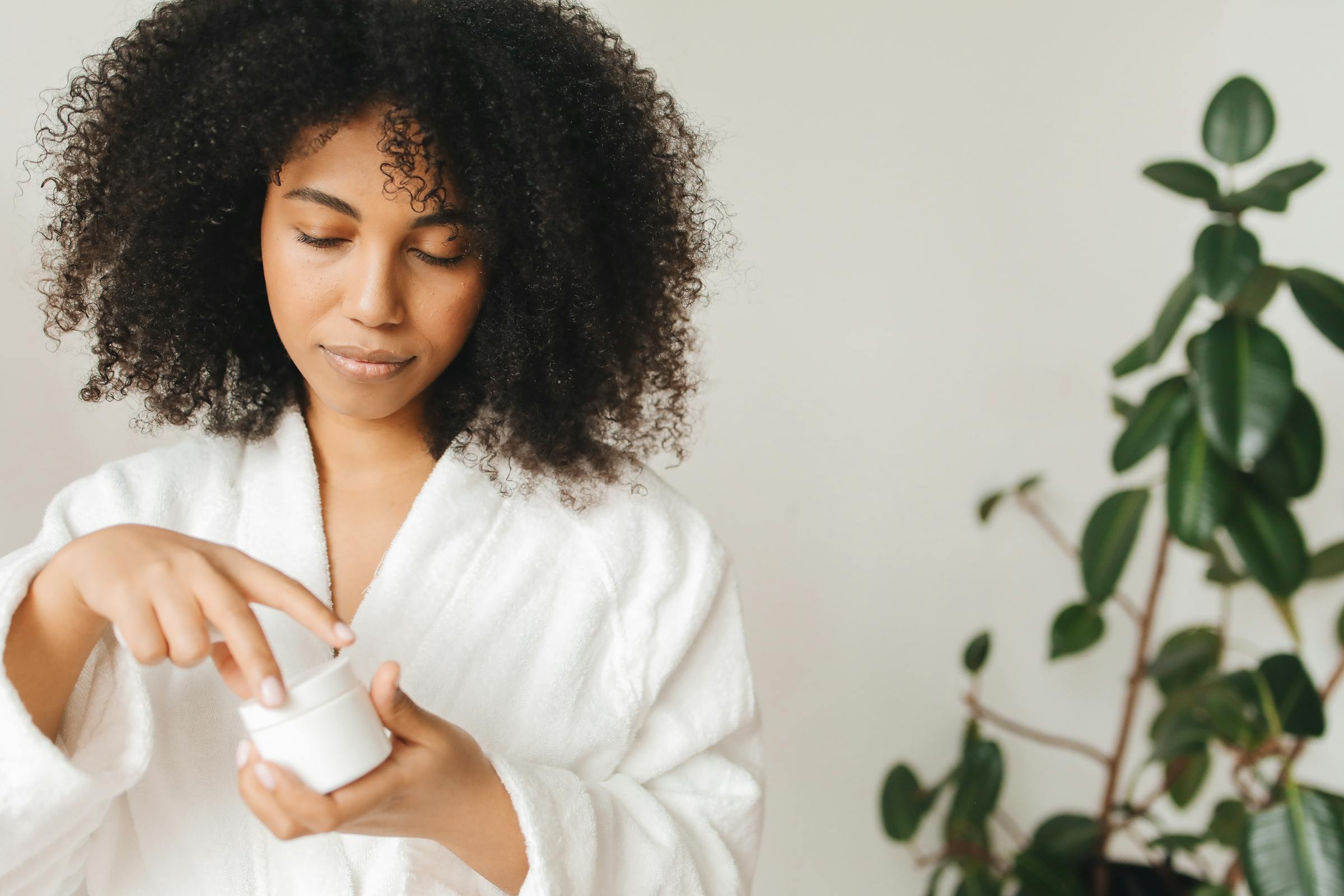 A woman applying skincare in soft natural light