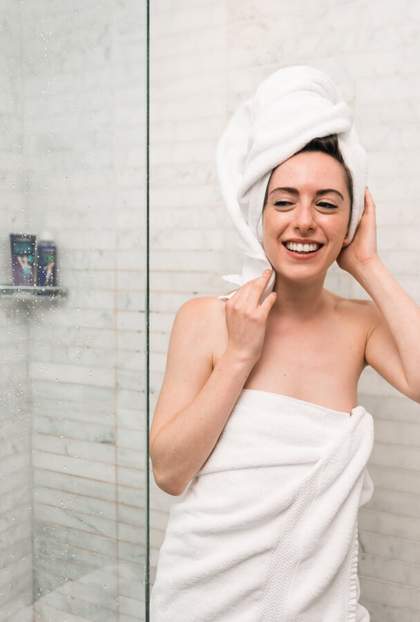 A woman wrapped in a towel getting out of a shower